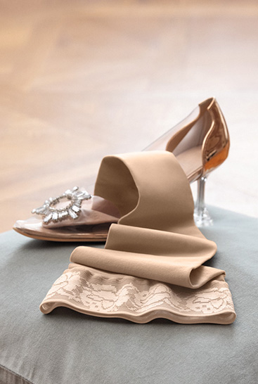 Juzo Soft Sesame lying on a cushion next to a Cinderella shoe