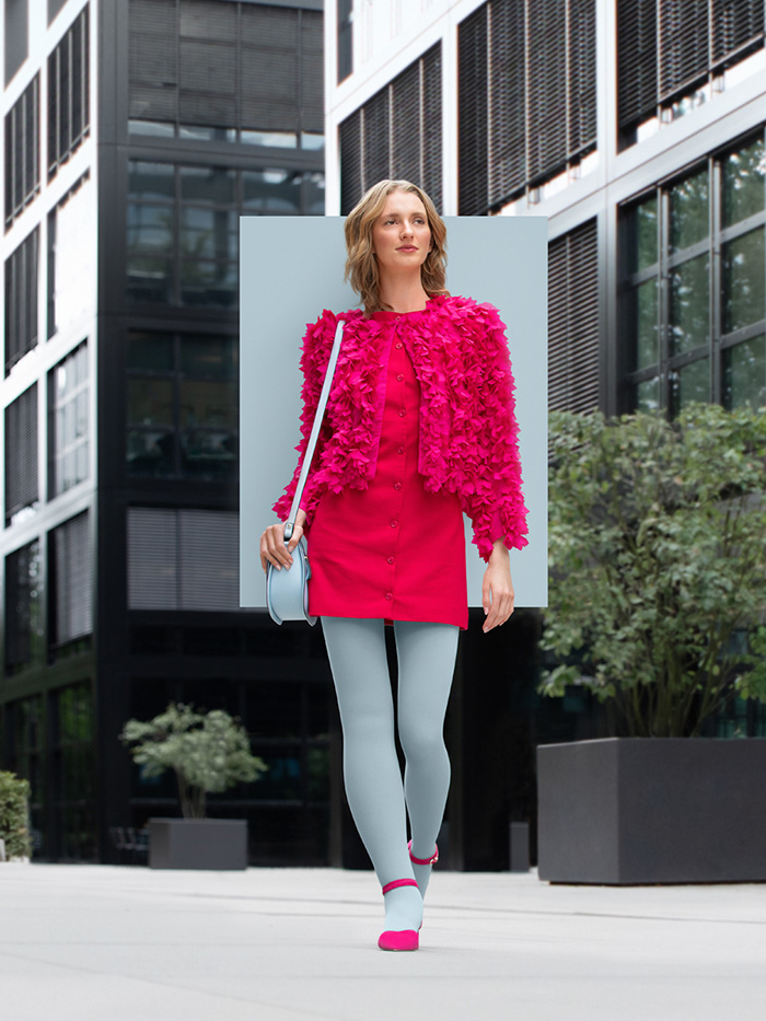 A woman with lymphoedema walks through the city wearing an Icy Blue compression garment with a pink dress