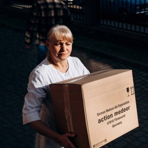 Juzo unterstützt Ukraine Frau trägt ein Hilfspaket