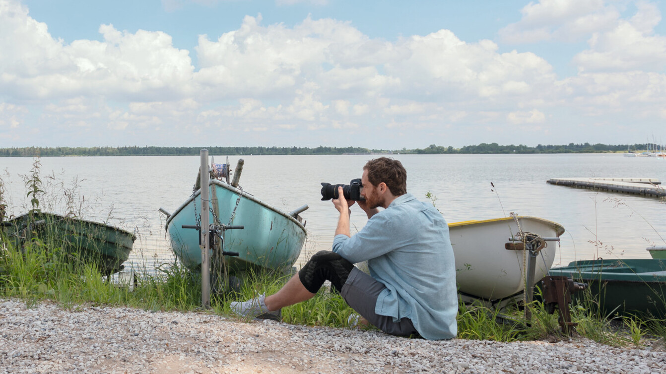 A man is sitting on the floor taking photos. He is wearing a knee brace. A man is sitting on the floor taking photos. He is wearing a knee brace.