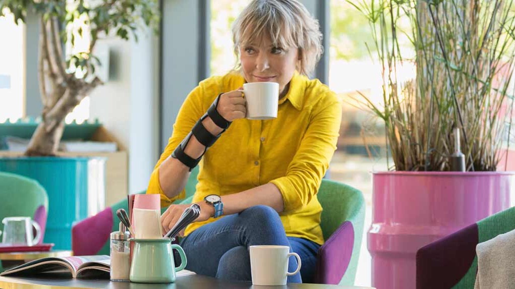 Frau trägt JuzoPro Manu Xtec Handgelenkorthese und hält eine Tasse in der Hand