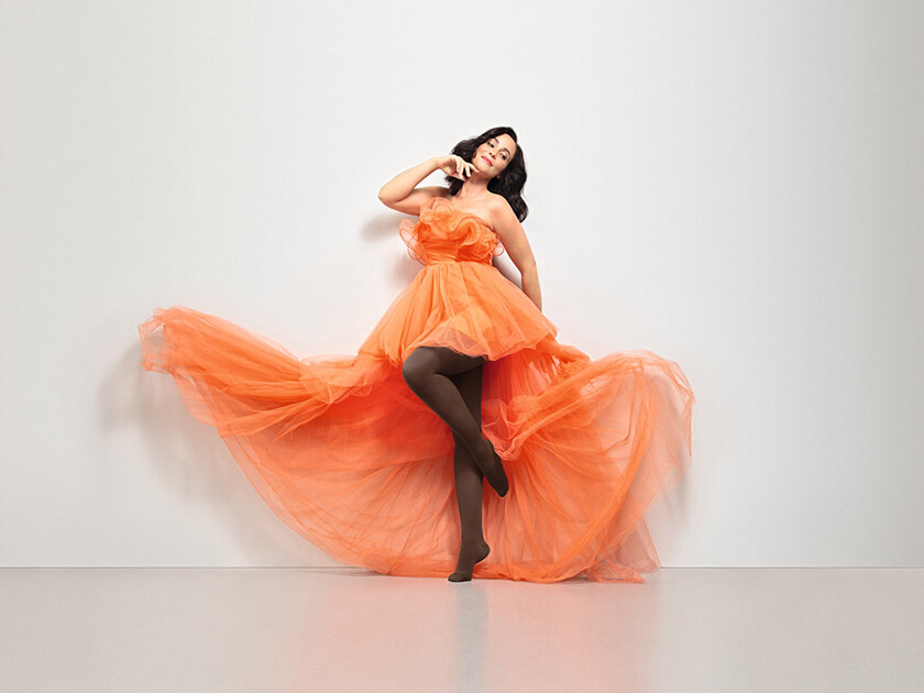 A woman in an orange dress. She is wearing Juzo Inspiration brown tights. A woman in an orange dress. She is wearing Juzo Inspiration brown tights.