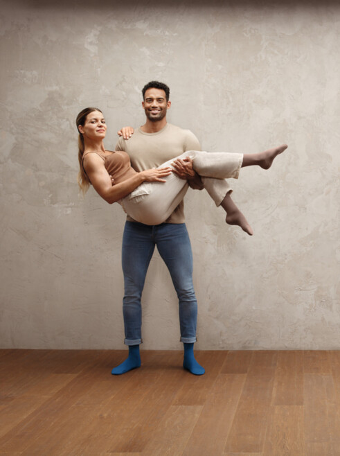 Man carrying woman in his arms, both wearing Juzo Intenso stockings