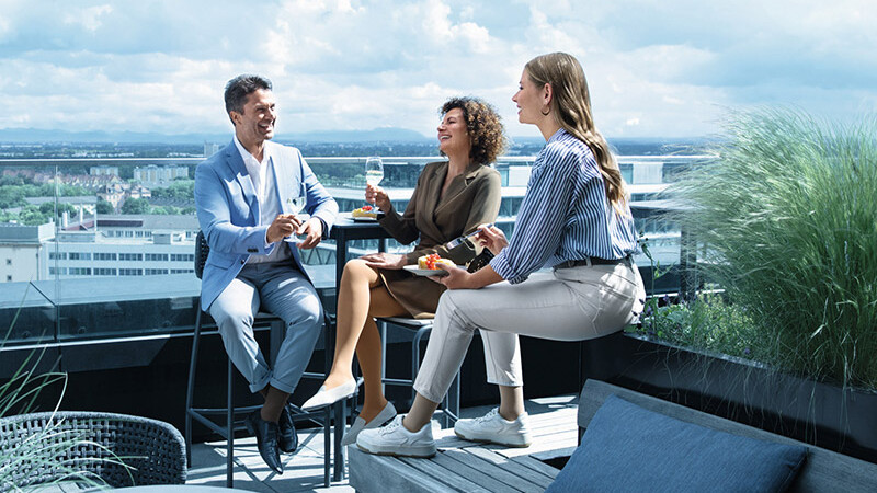 Un homme et deux femmes portant des bas de contention se trouvent sur une terrasse sur le toit. Un homme et deux femmes portant des bas de contention se trouvent sur une terrasse sur le toit.